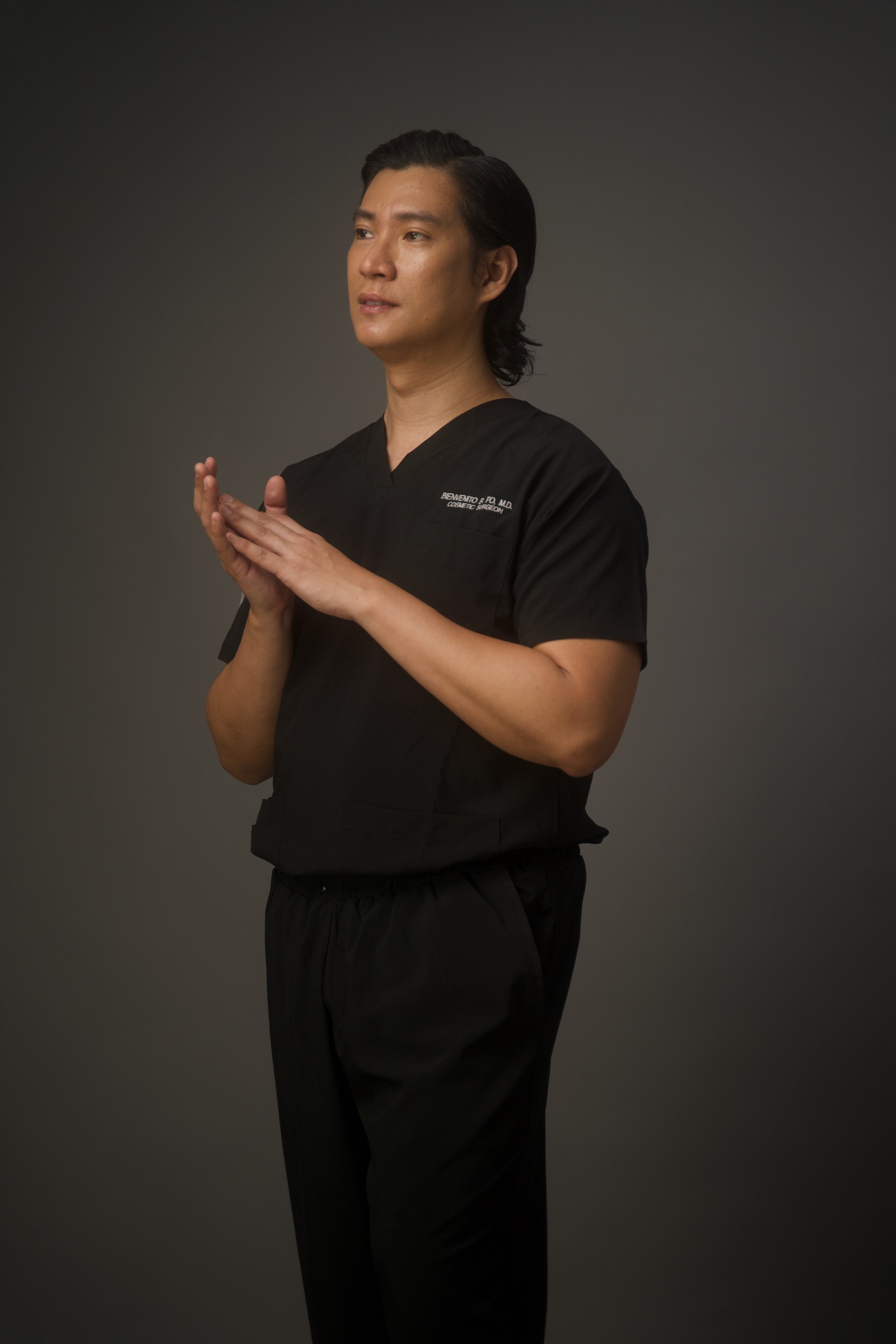 Dr. Bien Po standing in black surgical scrubs